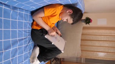 Bir çocuk kanepede otururken tahta üzerine bir kalemle resim çizer..