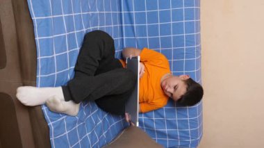 Bir çocuk kanepede otururken tahta üzerine bir kalemle resim çizer..