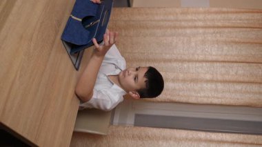 Bir çocuk masada otururken tablette oyunlar oynuyor..