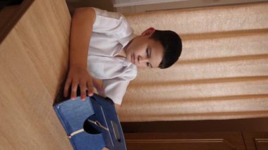 Bir çocuk masada otururken tablette oyunlar oynuyor..