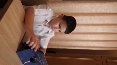 Bir çocuk masada otururken tablette oyunlar oynuyor..