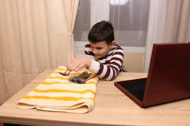 Oğlan çatal ve mutfak bıçaklarını siliyor. Ev işleri..