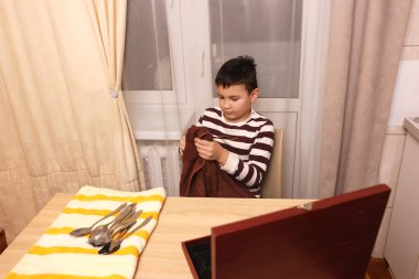 Oğlan çatal ve mutfak bıçaklarını siliyor. Ev işleri..