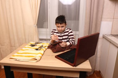 Oğlan çatal ve mutfak bıçaklarını siliyor. Ev işleri..