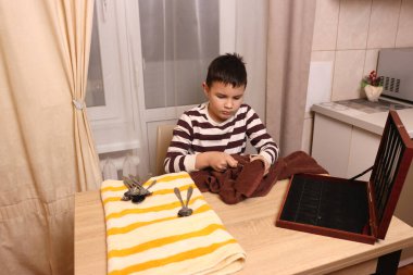 Oğlan çatal ve mutfak bıçaklarını siliyor. Ev işleri..