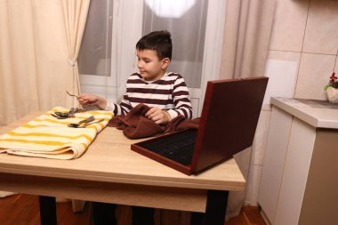 Oğlan çatal ve mutfak bıçaklarını siliyor. Ev işleri..