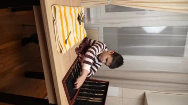 Oğlan çatal ve mutfak bıçaklarını siliyor. Ev işleri..