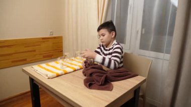 Oğlan bardakları ve bardakları havluyla siler. Ev işleri..