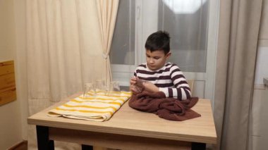 Oğlan bardakları ve bardakları havluyla siler. Ev işleri..