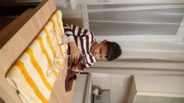 Oğlan bardakları ve bardakları havluyla siler. Ev işleri..