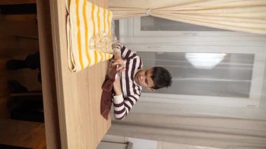 Oğlan bardakları ve bardakları havluyla siler. Ev işleri..