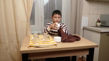 Oğlan bardakları ve bardakları havluyla siler. Ev işleri..