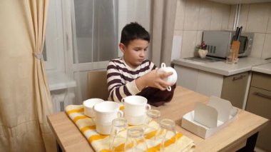 Oğlan bardakları ve bardakları havluyla siler. Ev işleri..