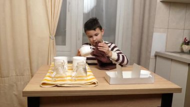 Oğlan bardakları ve bardakları havluyla siler. Ev işleri..