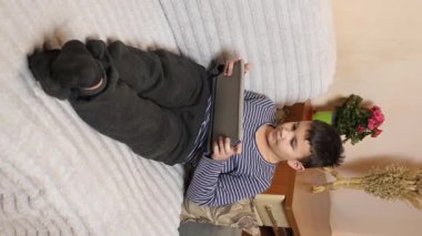 Bir çocuk kanepede otururken tablette oyun oynuyor..