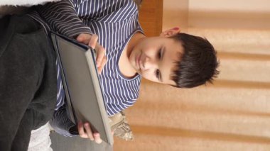 Bir çocuk kanepede otururken tablette oyun oynuyor..