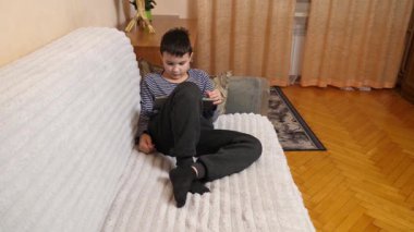Bir çocuk kanepede otururken tablette oyun oynuyor..