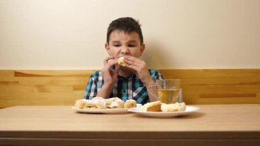 Bir çocuk masada otururken kurabiye yer ve çay içer..