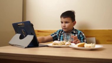 Bir çocuk masada otururken kurabiye yer ve çay içer..