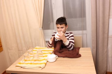 Oğlan bardakları ve bardakları havluyla siler. Ev işleri..