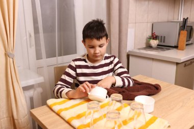 Oğlan bardakları ve bardakları havluyla siler. Ev işleri..