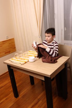 Oğlan bardakları ve bardakları havluyla siler. Ev işleri..