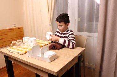 Oğlan bardakları ve bardakları havluyla siler. Ev işleri..