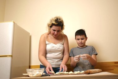 Bir çocuk ve annesi elmalı puf böreği yapıyorlar. Ev yemeği..