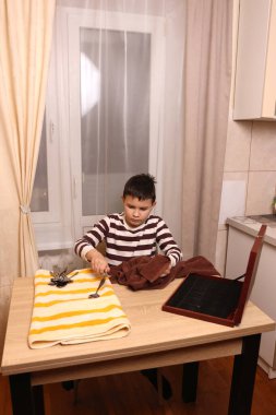 Oğlan çatal ve mutfak bıçaklarını siliyor. Ev işleri..