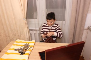 Oğlan çatal ve mutfak bıçaklarını siliyor. Ev işleri..