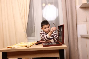 Oğlan çatal ve mutfak bıçaklarını siliyor. Ev işleri..