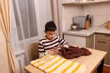 Oğlan bardakları ve bardakları havluyla siler. Ev işleri..