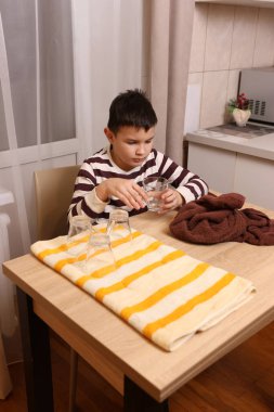 Oğlan bardakları ve bardakları havluyla siler. Ev işleri..