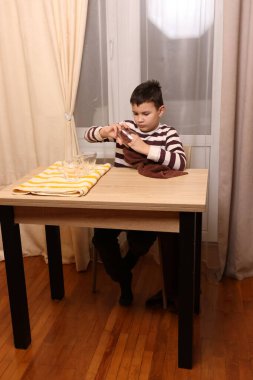 Oğlan bardakları ve bardakları havluyla siler. Ev işleri..