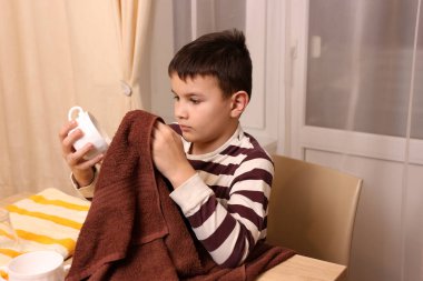 Oğlan bardakları ve bardakları havluyla siler. Ev işleri..