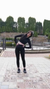 Genç bir kız dışarıda bir dinlenme tesisinde fiziksel egzersiz yapıyor..