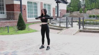 Genç bir kız dışarıda bir dinlenme tesisinde fiziksel egzersiz yapıyor..