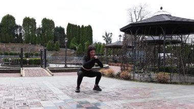 Genç bir kız dışarıda bir dinlenme tesisinde fiziksel egzersiz yapıyor..