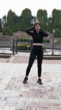 Genç bir kız dışarıda bir dinlenme tesisinde fiziksel egzersiz yapıyor..