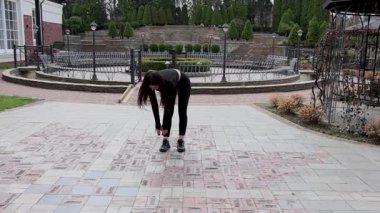 Genç bir kız dışarıda bir dinlenme tesisinde fiziksel egzersiz yapıyor..