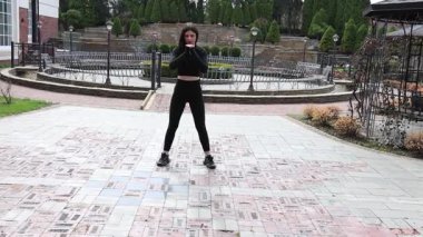 Genç bir kız dışarıda bir dinlenme tesisinde fiziksel egzersiz yapıyor..