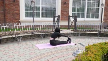 Genç bir kız dışarıda bir dinlenme tesisinde fiziksel egzersiz yapıyor..