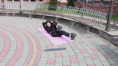 Genç bir kız dışarıda bir dinlenme tesisinde fiziksel egzersiz yapıyor..