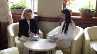 Masadaki kafede konuşan ve kahve içen iki kadın..