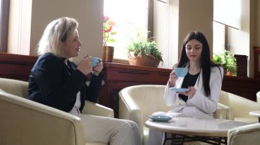 Masadaki kafede konuşan ve kahve içen iki kadın..