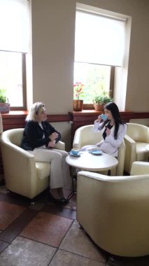 Masadaki kafede konuşan ve kahve içen iki kadın..