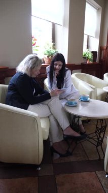 Masadaki kafede konuşan ve kahve içen iki kadın..