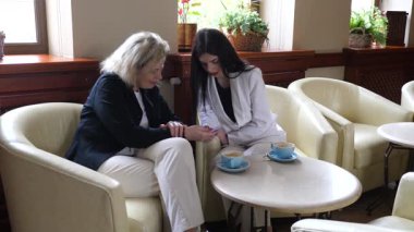 Masadaki kafede konuşan ve kahve içen iki kadın..