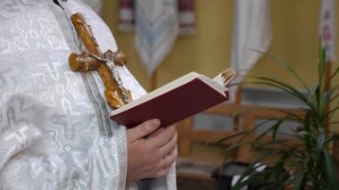 Elinde haç olan bir rahip ayin sırasında kitap okur..
