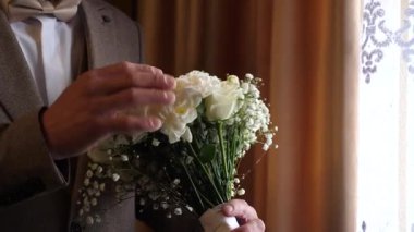 Damat elinde güzel bir düğün buketi tutuyor..